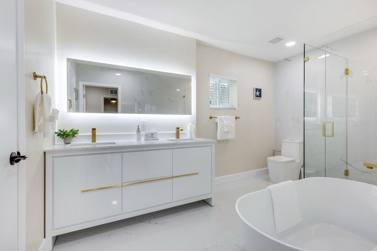 Renovated bathroom with double vanity, LED mirror, and freestanding tub