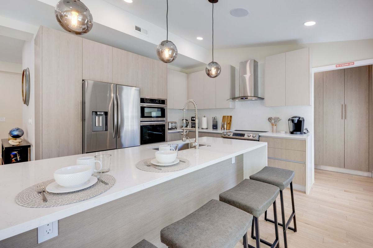 Renovated kitchen with white quartz waterfall island and pendant lighting