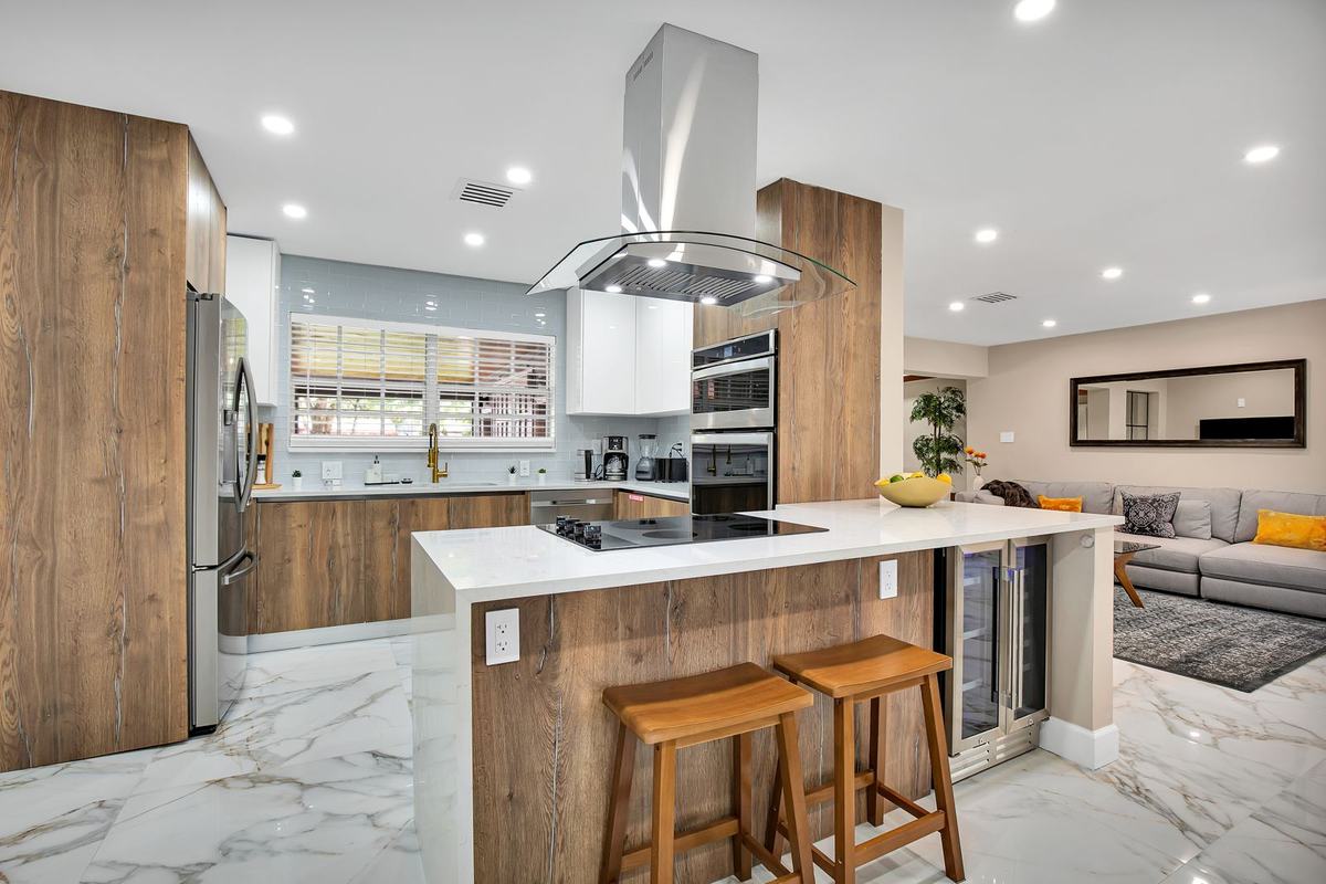 Renovated kitchen with wood cabinetry, marble floors, and island seating