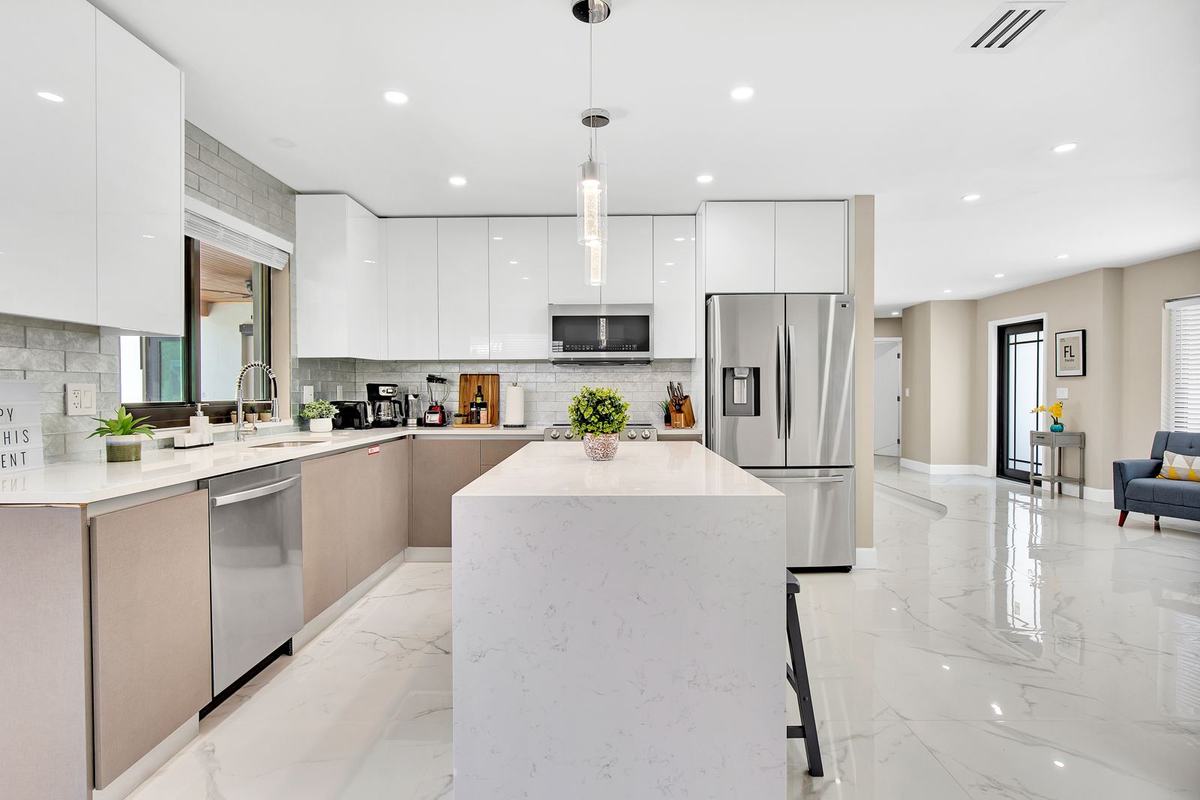 Renovated white kitchen with quartz island and polished floors