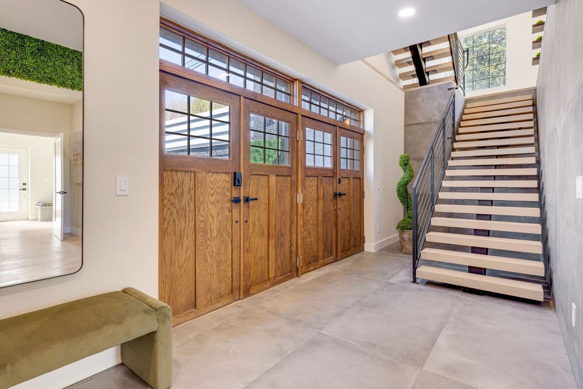 Renovated entry with floating staircase and custom wood garage doors
