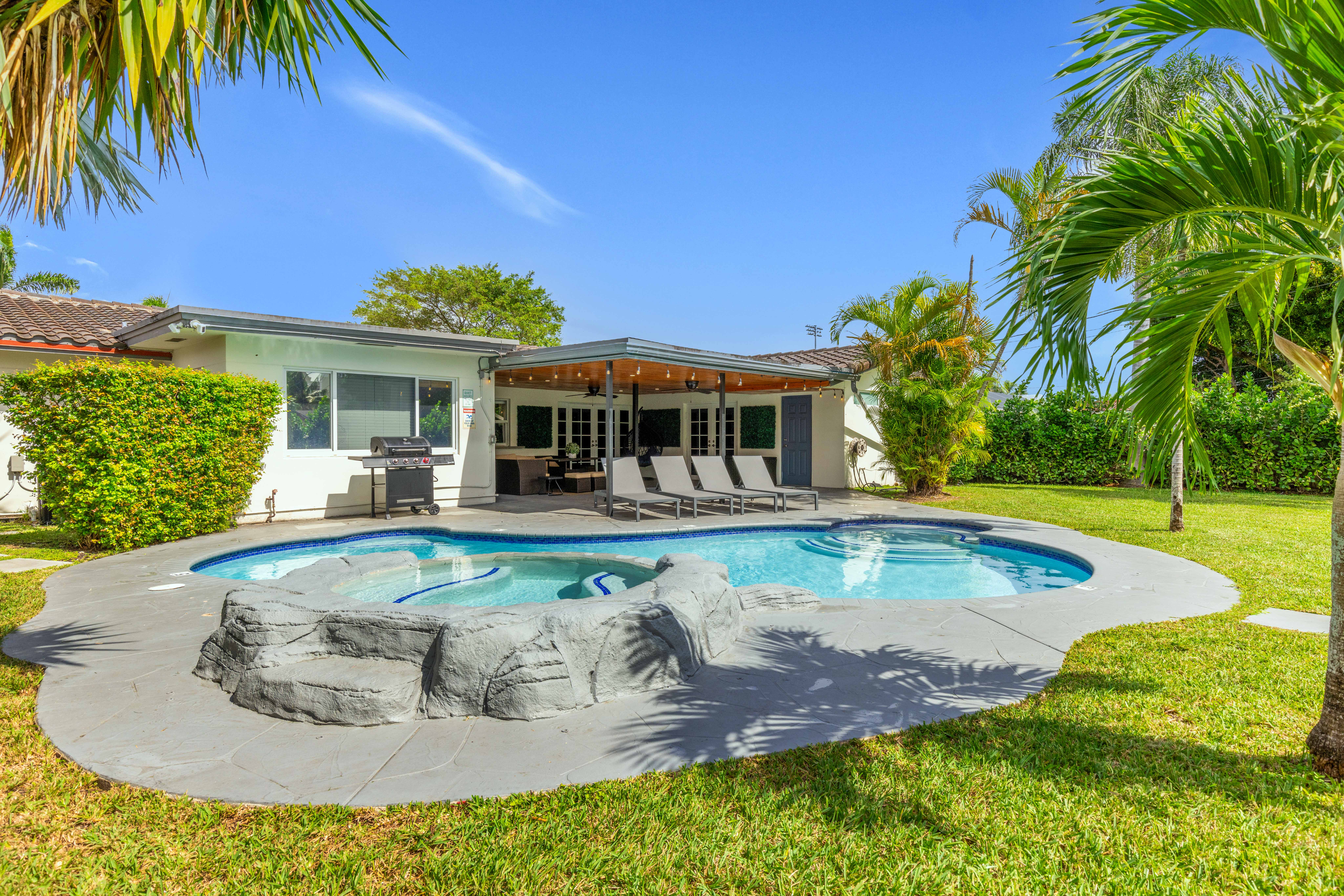The same backyard after renovation — filled pool, new patio, pergola, and landscaping