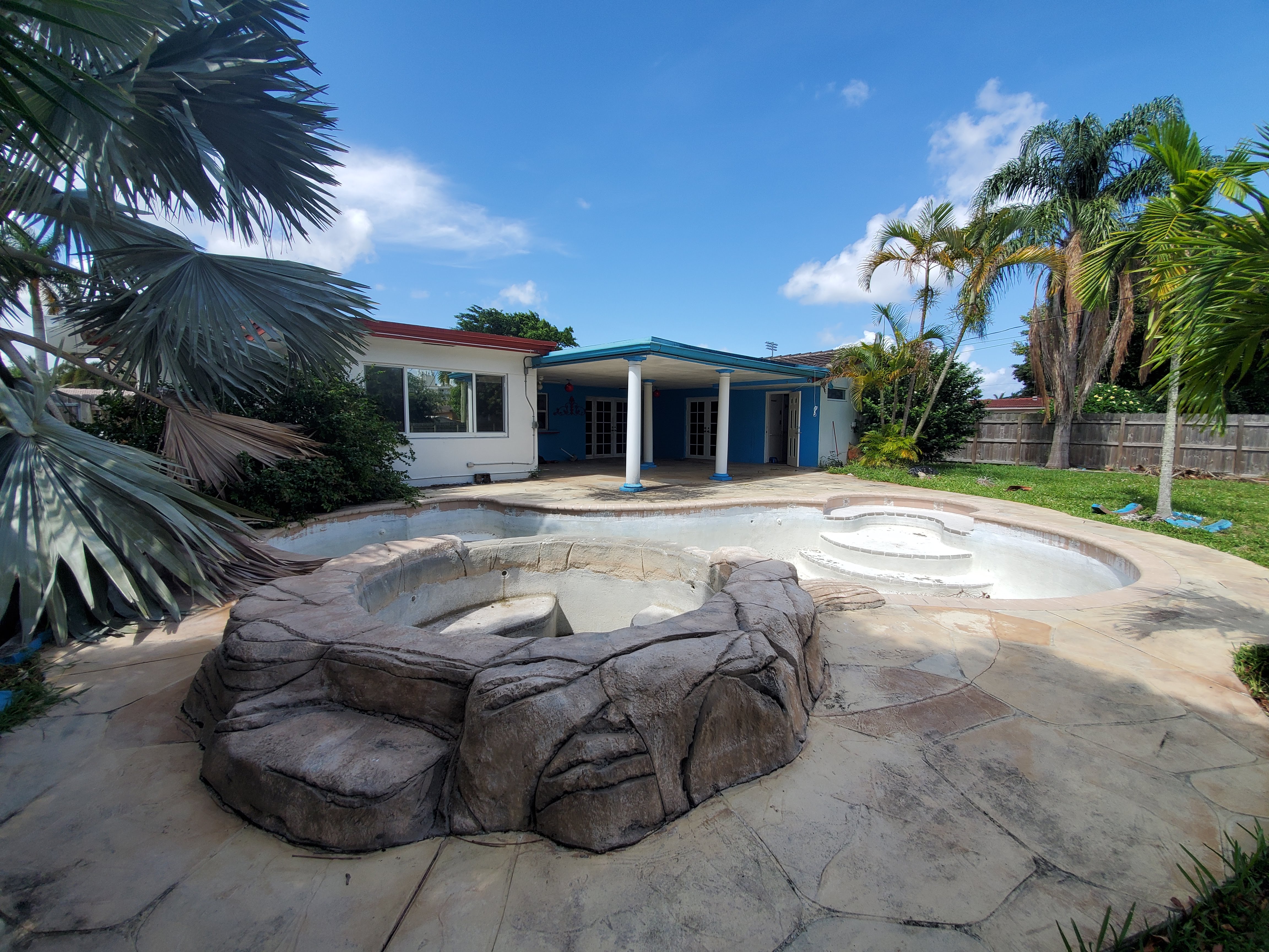Backyard with empty pool and worn patio before renovation